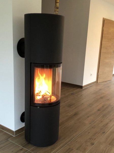Mattschwarzer Kaminofen in Tarnow mit Sicht auf Holzfeuer in Wohnzimmer mit hellem Parkettboden