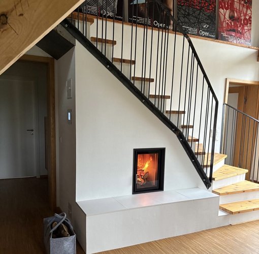 Heizkamin mit Sichtscheibe und Putz verbaut unter einer Treppe